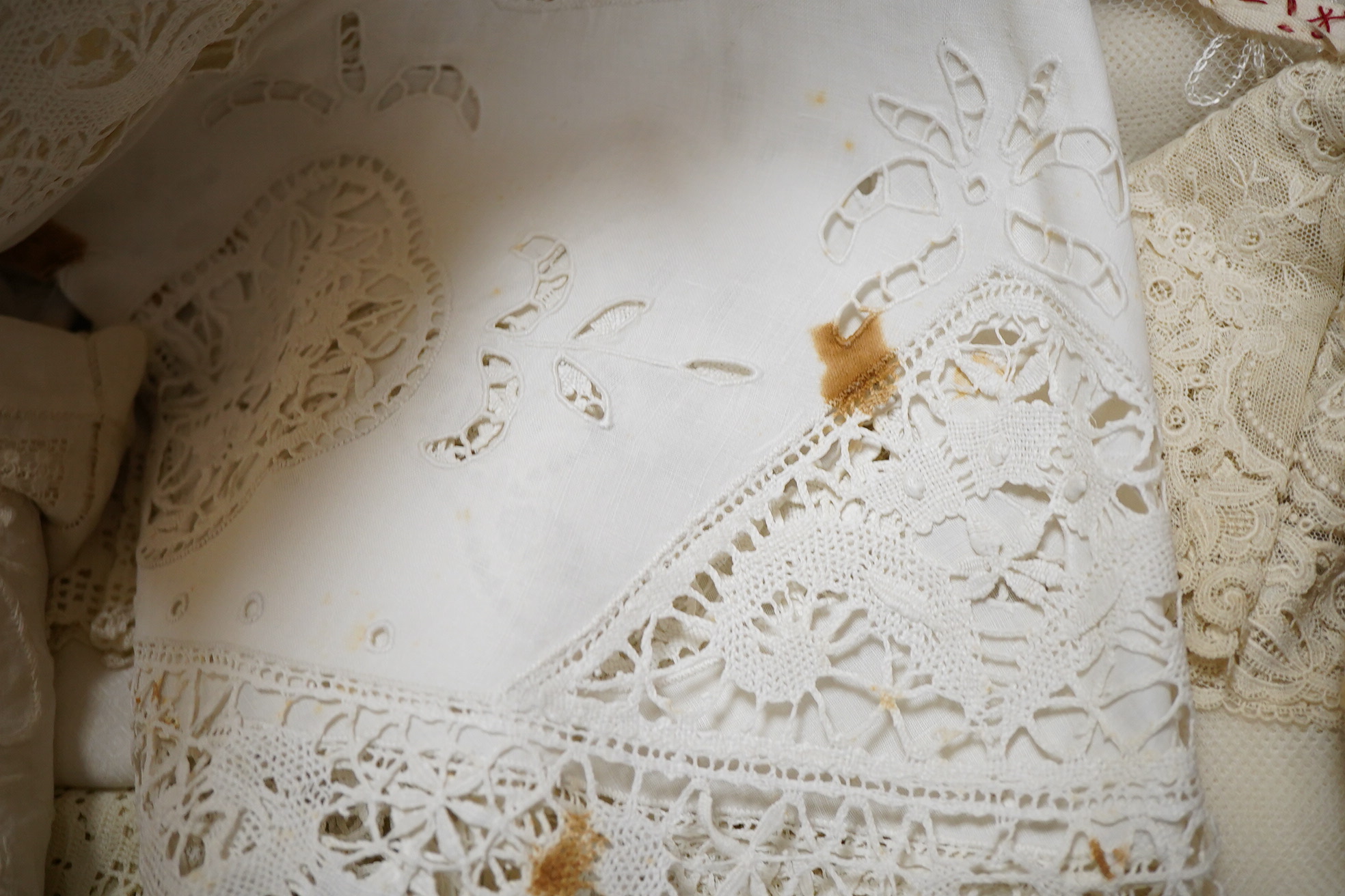 A small box/trunk containing mixed crochet, embroidered anglaise and drawn thread table linens, christening gown, damask cloths and various pieces of lace etc.Ornate circular cloth 112cm diameter. Condition - most need r